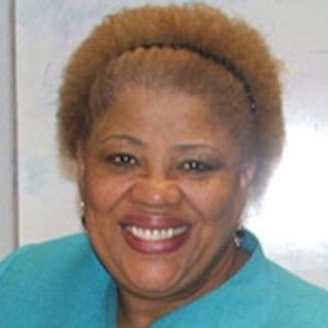 Smiling woman with natural hair wearing a teal top, representing Difference Makers Media’s diverse and dynamic team.