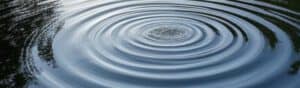 Ripple effect on calm water surface representing impact and influence in media and communication.