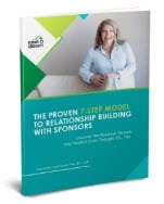 A smiling woman sitting confidently at a desk, representing relationship-building success with sponsors, in a professional office setting.