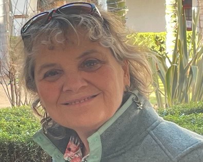 Portrait of a smiling empowerment coach with a warm expression, outdoor background with greenery, highlighting leadership and personal growth.