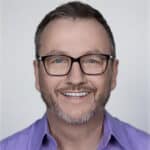 Smiling man with glasses giving a testimonial for Difference Makers Media, showcasing client satisfaction and positive feedback.