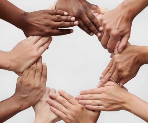 Diverse hands joined together in a circle symbolizing teamwork, unity, and collaboration for success in business and community initiatives.